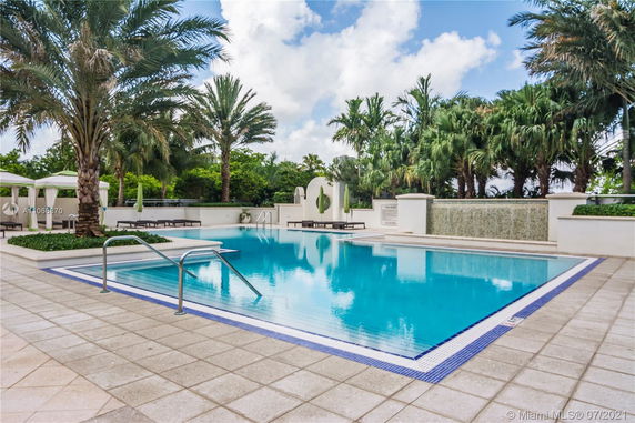 Outdoor swimming pool with surrounding palm trees and lounge areas.
