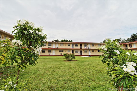 Front view of a two-story apartment building with a grassy area in the foreground.