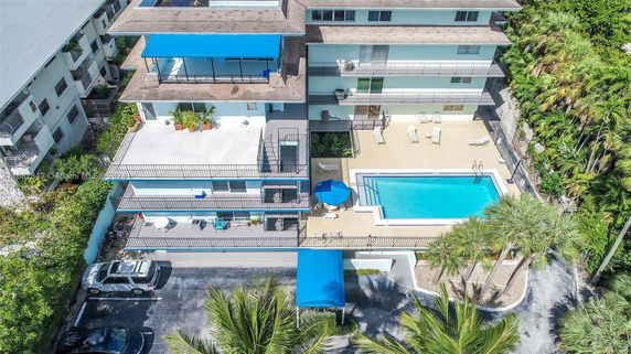 Aerial view of a multi-story building with a swimming pool on a terrace.