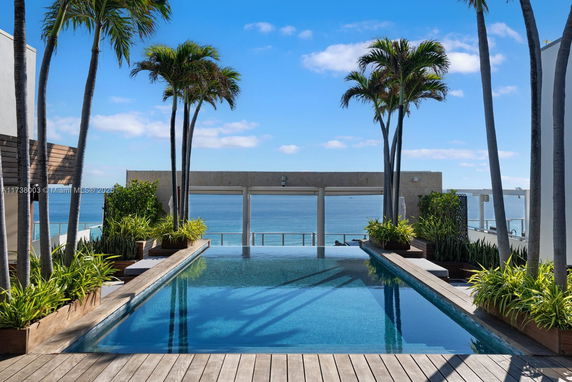 Rooftop swimming pool with ocean view and palm trees.