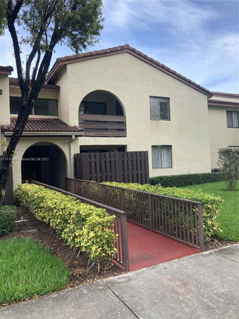 Front view of a two-story house with a balcony and pathway.