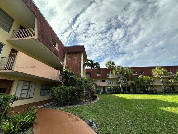 Front view of a multi-story residential building with balconies and a sloped roof.