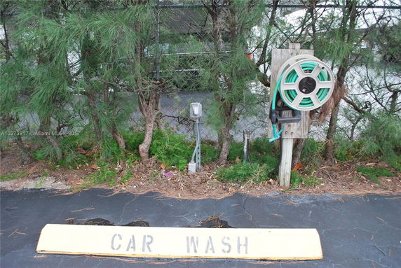 Outdoor car wash area with a hose reel attached to a post.