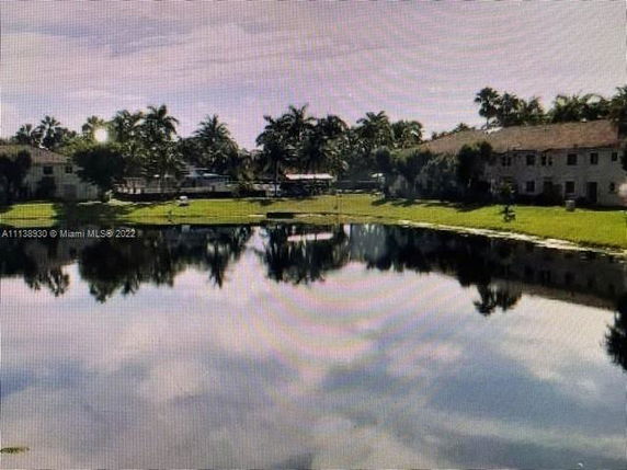 Buildings by a reflective pond with palm trees in the background