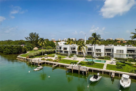 Panoramic view of waterfront apartments with a swimming pool and dock area.