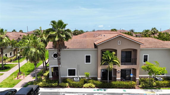 Front view of a two-story building with a tiled roof and a small balcony.