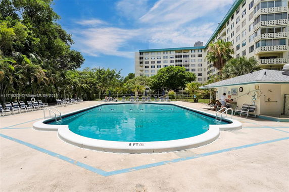 Outdoor swimming pool area with lounge chairs and adjacent building.