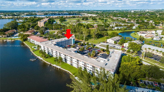 Aerial view of a large apartment complex near a body of water with surrounding residential areas and greenery.