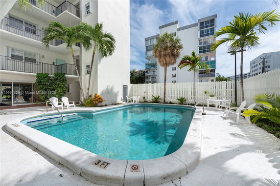 Outdoor swimming pool area beside a multi-story building.