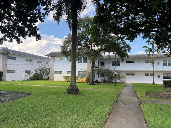 Front view of a two-story residential building with a central entrance and surrounding walkway.