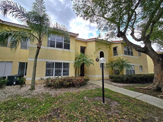 Front view of a two-story yellow building with trees in front.