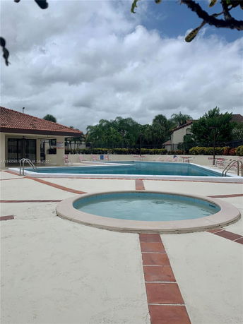 Outdoor swimming pool area with a circular hot tub and lounge chairs.