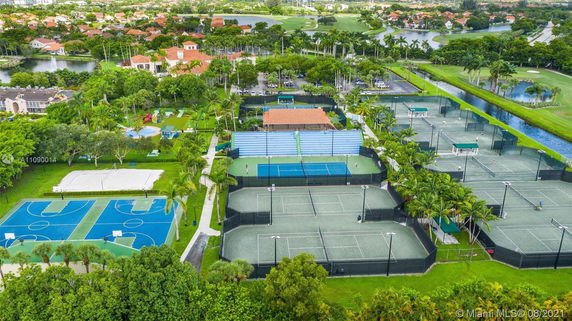 Aerial view of sports complex with multiple tennis courts, basketball courts, and a playground area.