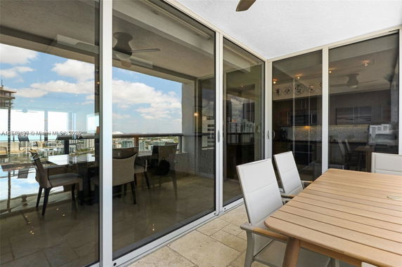 Glass-walled balcony with outdoor seating offering views of surrounding city buildings.