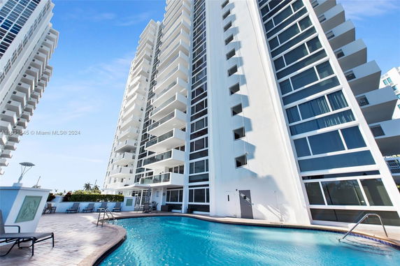View of a modern high-rise building with balconies, adjacent to a swimming pool.