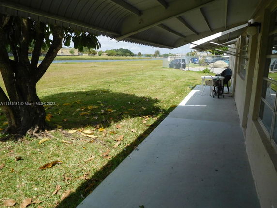 Side patio view of a building with grassy area and tree in the foreground.