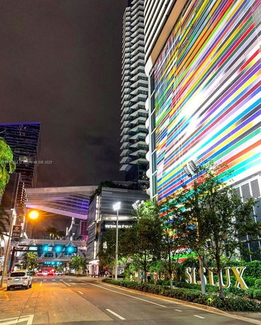 Front view of a tall building with colorful vertical stripes and adjacent structures.