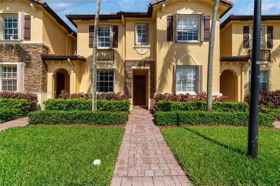 Front view of a two-story townhouse with stucco exterior and stone accents.
