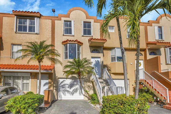 Front view of a multi-story townhouse with palm trees.
