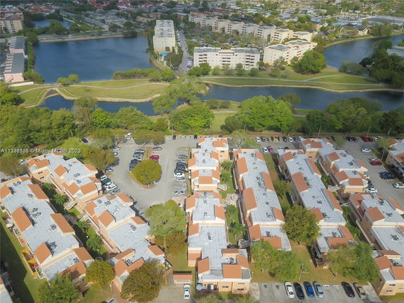Aerial view of a residential area with multiple apartment buildings, parking lots, and a nearby lake.