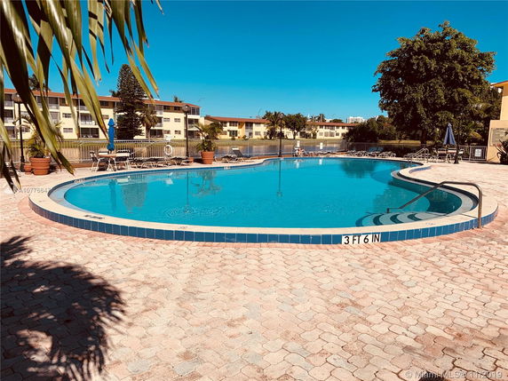 Outdoor swimming pool area with nearby buildings.