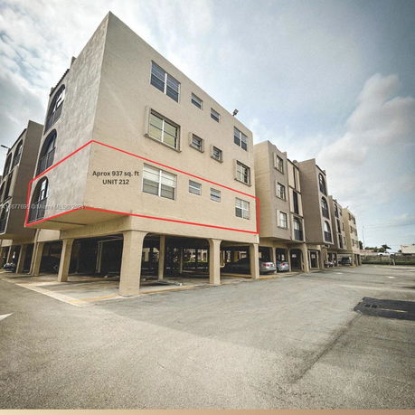 Front view of a multi-story apartment building with parking on the ground level.