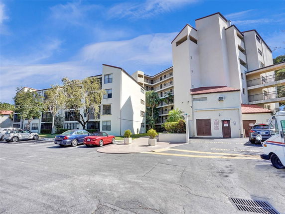 Front view of a multi-story residential building with parking area.