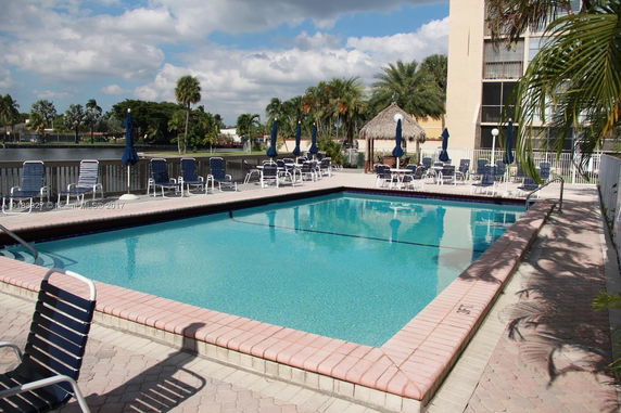 Outdoor swimming pool area with surrounding lounge chairs and umbrellas.