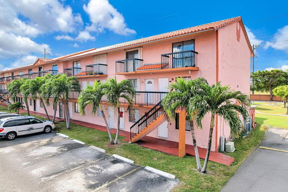 Front view of a multi-story residential building with external staircases and balconies.