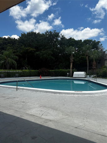Outdoor swimming pool area with surrounding trees.