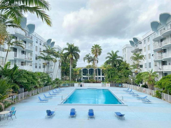 Outdoor swimming pool area surrounded by multi-story residential buildings.
