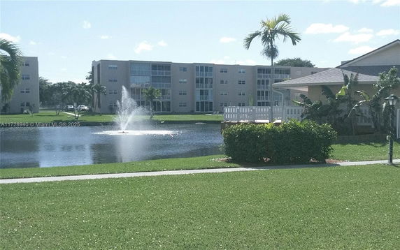 View of apartment buildings with a pond and fountain in the foreground.