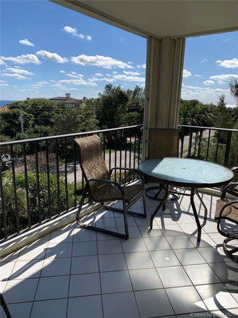 View from a balcony looking out towards distant houses and greenery.