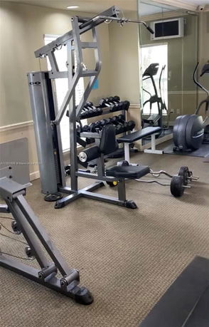 Indoor gym area with exercise equipment including weights and machines.