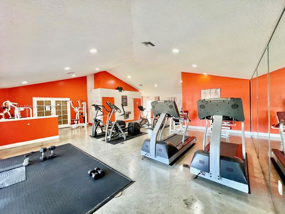 Indoor gym with treadmills, exercise equipment, and mirrored wall.
