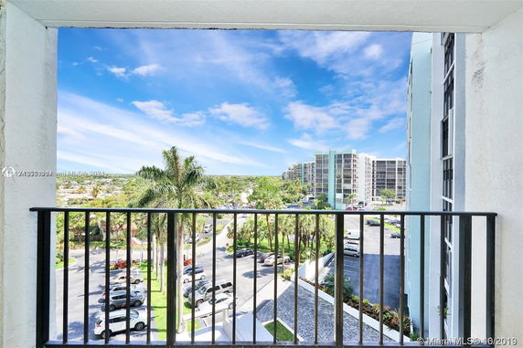 View from a balcony overlooking a parking lot with tall buildings in the background.