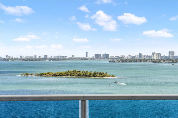 A view of a body of water with a small island and city skyline in the distance.