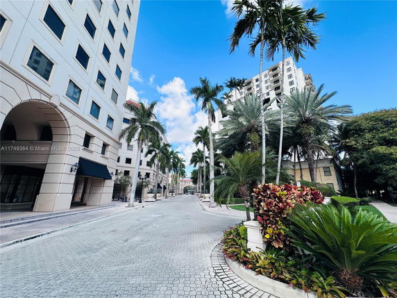 Street view in an urban area with tall buildings and palm trees.