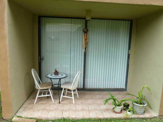 Small patio area with two chairs and a table in front of sliding glass doors.
