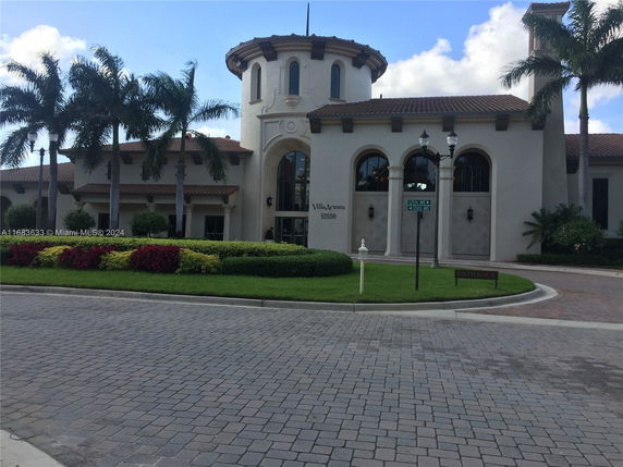 Front view of a large, multi-story building with arched windows and decorative landscaping.