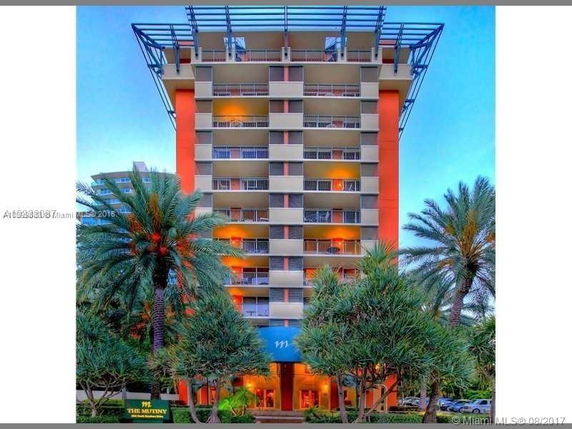 Front view of a multi-story building with balconies and orange accents.