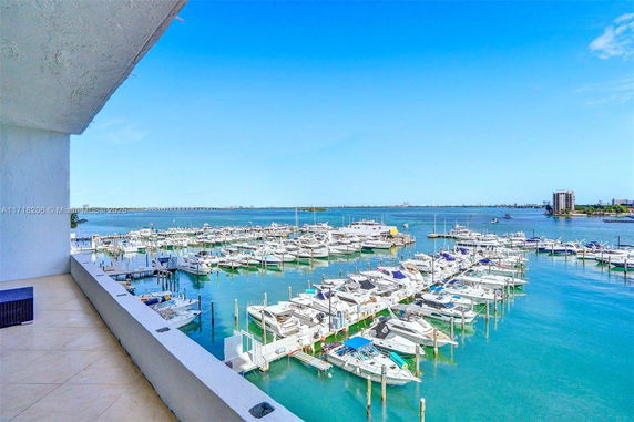 Panoramic view of a marina with numerous boats docked and a clear blue sky.