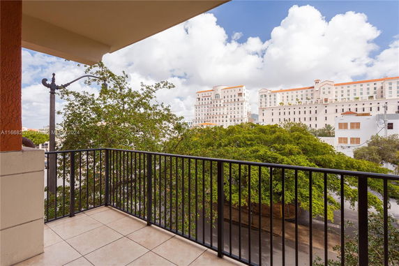 View from a balcony overlooking a multi-story building with trees below.