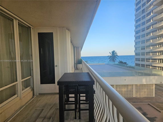 Balcony view with furniture overlooking the ocean and adjacent buildings.