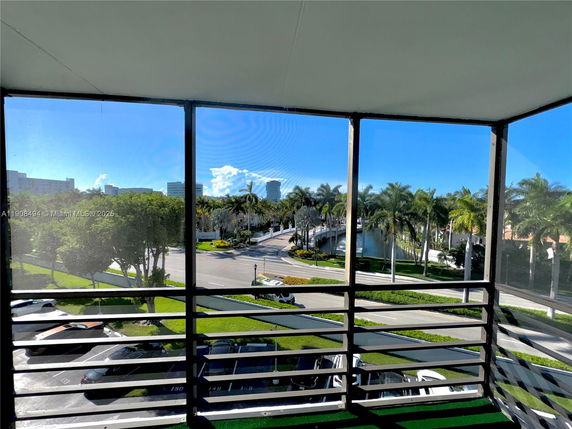 Panoramic view from a building showing palm trees, a road, and distant buildings.