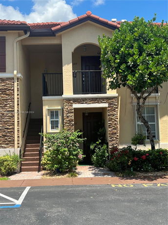 Front view of a two-story house with a balcony and stone accents.