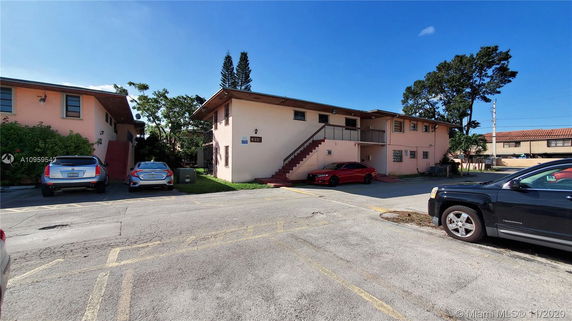 Front view of a two-story building with exterior stairs and parking area.