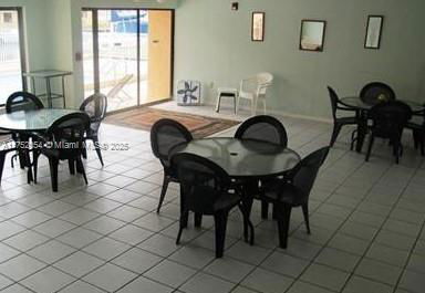 Indoor recreational area with tables and chairs on a tiled floor.