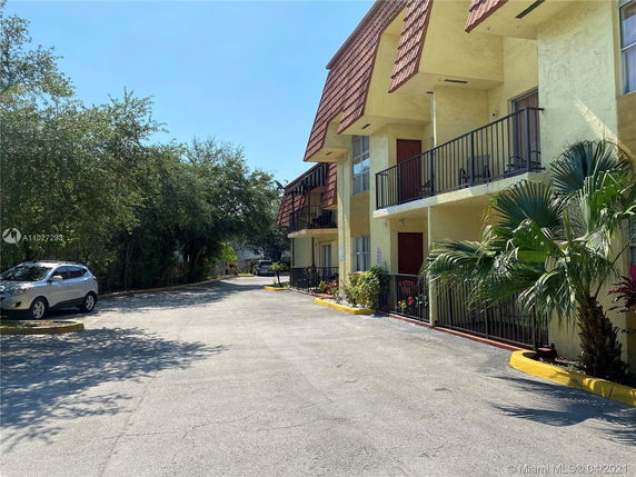 Outdoor parking area adjacent to a residential building with balconies.
