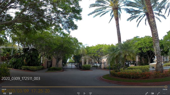 Gated entrance surrounded by tropical trees and landscaping.